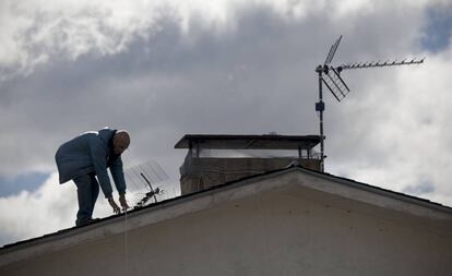 Un hombre cambia una antena antigua en una vivienda de Madrid.