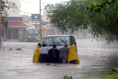 Habitantes de Cancún intentan mover un vehículo atrapado entre las aguas, tras lal fuertes lluvias provocadas por la entrada del huracán Wilma.