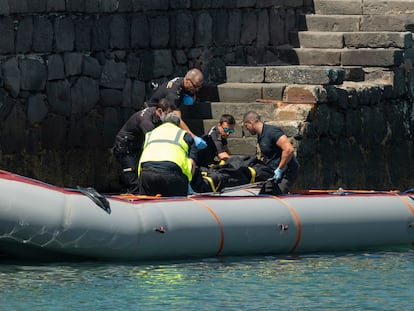 Dos trabajadores de traslados fúnebres y tres agentes de la Policía Nacional desembarcan el cadáver de la mujer embarazada que llegó sin vida al puerto de Arrecife (Lanzarote).