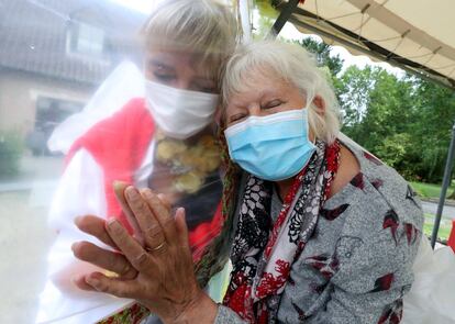 Lily Hendrickx, de 83 años, residente en el hogar de ancianos belga "Le Jardin de Picardie" abraza a Marie-Christine Desoer, la directora de la residencia, a través un plástico para protegerse contra una posible infección por coronavirus, en Peruwelz, Bélgica.