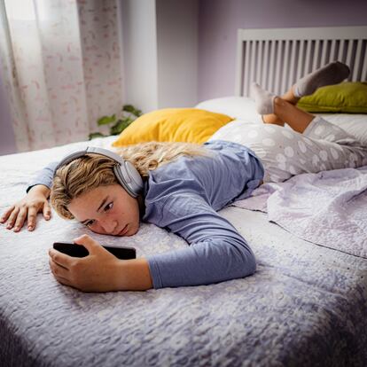 Relaxed teen girl listening music laying on her bedroom.