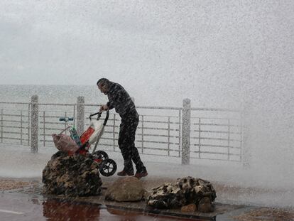 Un hombre bajo la lluvia y las olas en el paseo Nuevo de San Sebastían