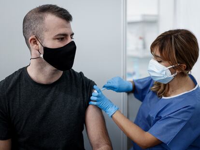 Una enfermera vacuna de la tercera dosis a un joven en Barcelona.
