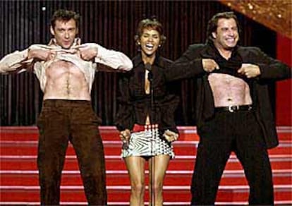 Hug Jackman y John Travolta acompañan a Halle Berry en el escenario.