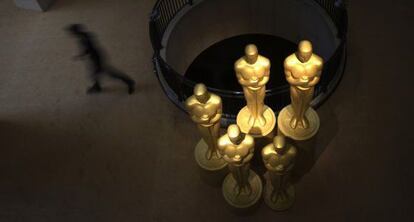 Un hombre camina junto a varias estatuas de los &#039;oscars&#039; en la entrada del Dolby Theatre.