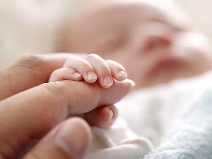 Un bebé agarra la mano de su padre. 