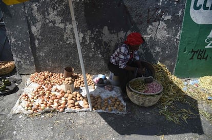 Entre as medidas anunciadas pelo primeiro-ministro Jean-Henry Céant estão a redução dos preços dos alimentos, a discussão com o setor privado de um possível aumento do salário mínimo, bem como a redução de 30% do orçamento de seu gabinete, que ele espera que seja replicado por Presidência e Parlamento. Na foto, uma mulher vende seus produtos ao lado do mercado de Kokoyet, na comuna de Petion Ville, em Porto Príncipe, em 17 de fevereiro de 2019.