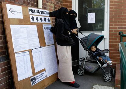 Dos mujeres con un niño espera a las puertas de un centro de votación en la circunscripción de Barking, al este de Londres.