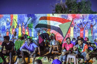 Un grupo de manifestantes sudaneses se sientan a descansar frente a un mural durante una protesta cerca del cuartel general del ejército en la capital, Jartum. 