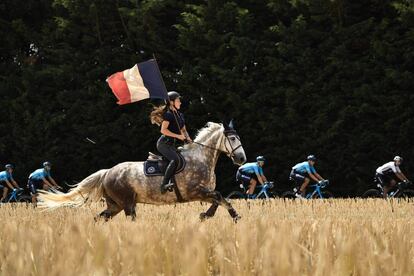 Un jinete agita una bandera francesa, en paralelo a la carrera ciclista, durante la octava etapa de la 105ª edición del Tour de Francia, entre Dreux y Amiens, en el norte de Francia, el 14 de julio de 2018.