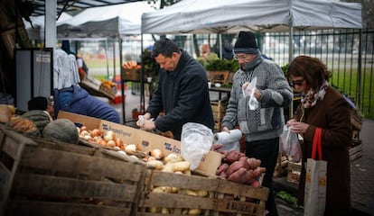 Un grupo de personas compra en un puesto callejero de frutas y verduras en Buenos Aires.