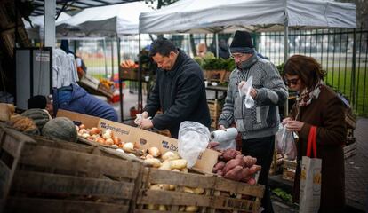 Un grupo de personas compra en un puesto callejero de frutas y verduras en Buenos Aires.