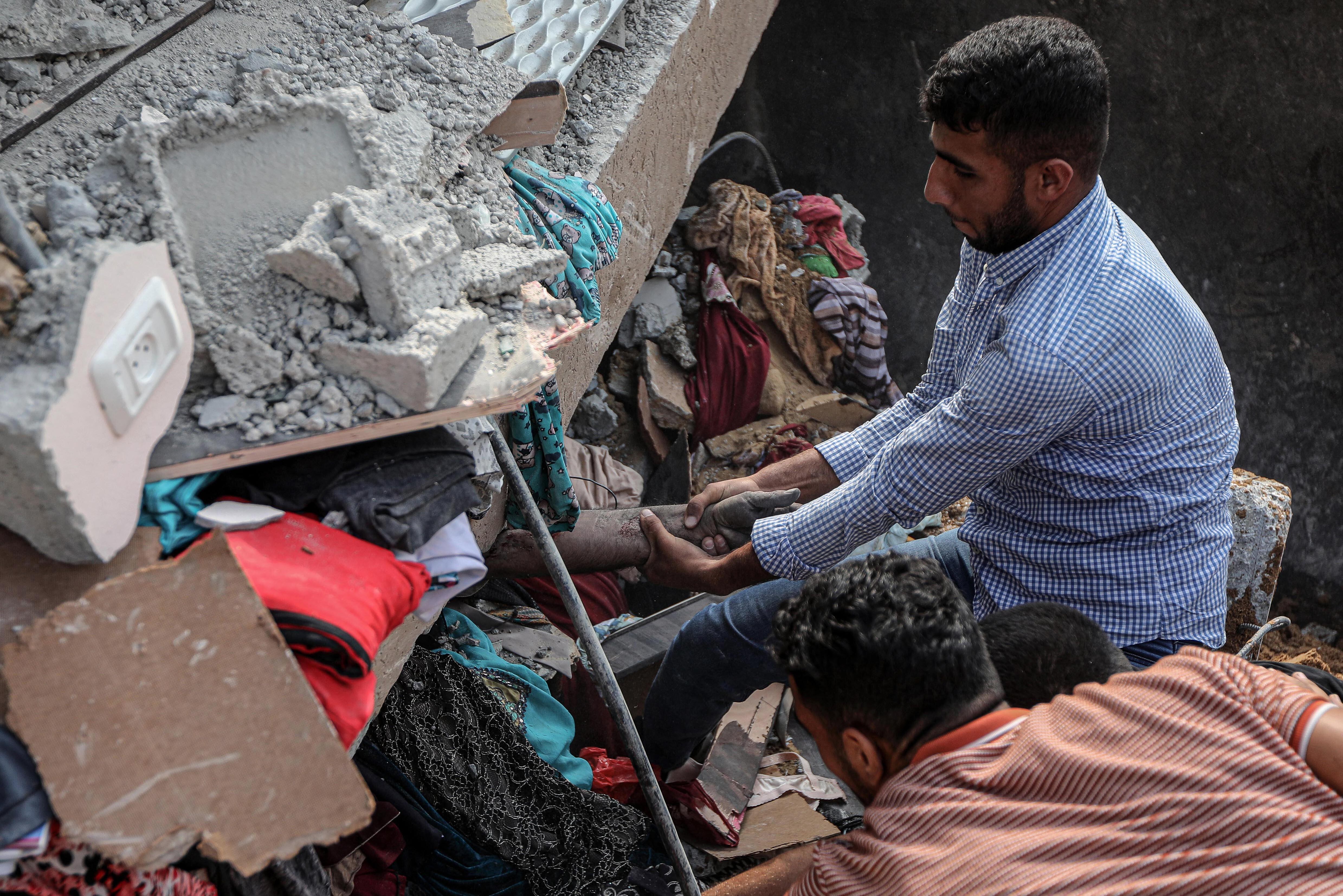 Una palestino intenta rescatar el cadáver de una persona atrapada entre los escombros de un edificio destruido tras un bombardeo israelí en Khan Yunis, este domingo.