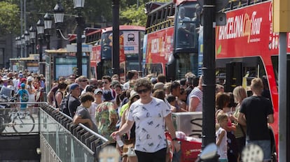 Grupos de turistas, en cola para acceder a un autobus turistico, en Barcelona.