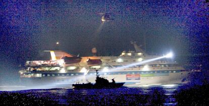 La silueta de una patrullera israelí se recorta sobre uno de los barcos de la <b>flotilla</b> durante el asalto.