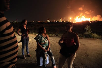 Varios miembros de la familia C&eacute;spedes contemplan el incendio despu&eacute;s de haber sido desalojados de su casa. 