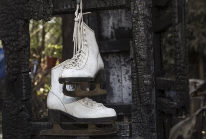 Colgados de un armario calcinado han quedado intactos dos pequeños patines de hielo. Indiferentes al caos que se vive a su alrededor, salpicado de cristales rotos, plásticos derretidos, jarrones hechos añicos, madera calcinada. Aquellas botitas blancas recuerdan que en ese mismo lugar, ahora negro, hasta hace no mucho vivió una familia. Al remover los escombros, asoman otros zapatos sueltos, alguna chaqueta, unos paraguas, fotografías antiguas. Y cientos de libros destrozados, pues la madre de Grace había hecho su fortuna con una de las pocas librerías especializadas que existían en la capital.