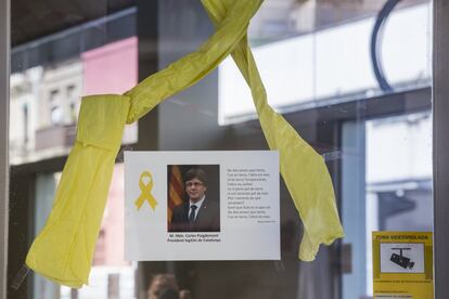 Detalle de la sede de la Agencia de Salud Pública de Cataluña, donde se observa a Carles Puigdemont junto a un lazo amarillo.