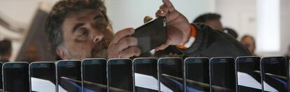 Un hombre inspecciona un teléfono móvil en una exposición.