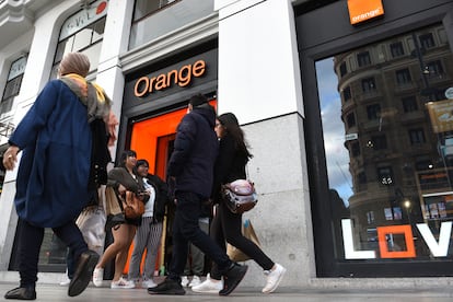 People are seen walking past an Orange SA Mobile Phone shop