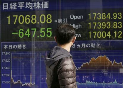 Un hombre pasa frente a una pantalla que muestra informaci&oacute;n del &iacute;ndice Nikkei de la Bolsa de Tokio.