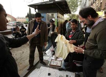 Clientes examinan la mercancía de un puesto de venta ilegal en Atocha.