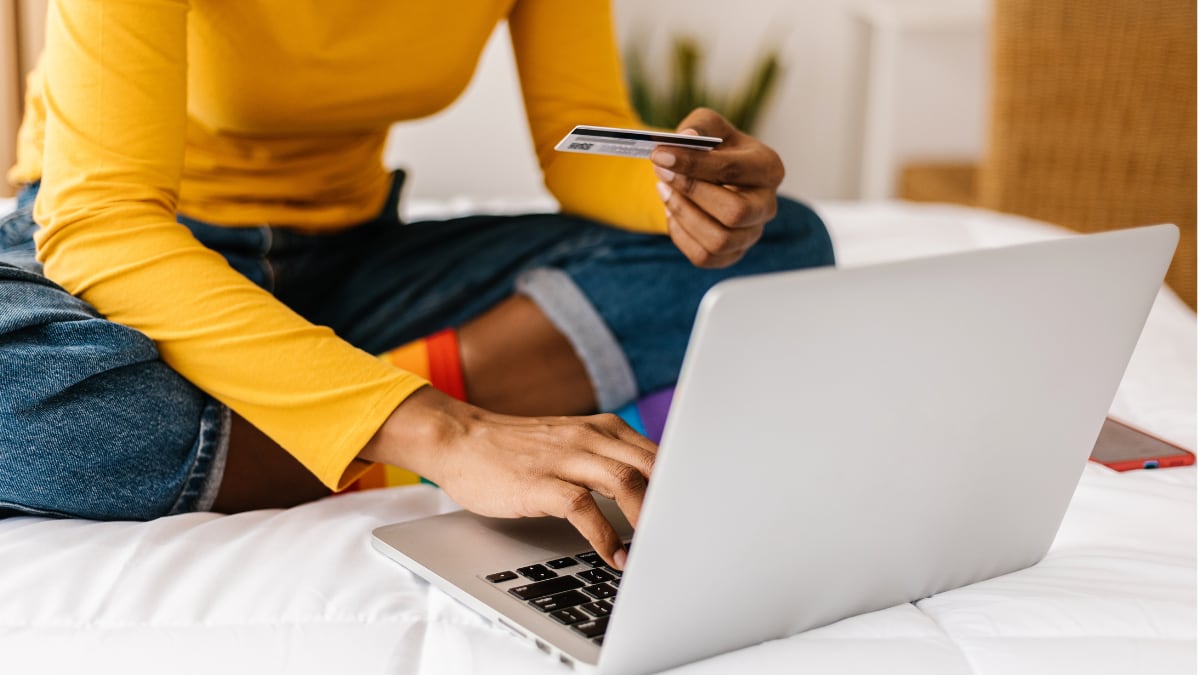 A woman using a credit card to shop online on a computer.