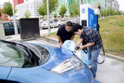 Un operario coloca junto al cliente el enchufe en el coche. EFE/Archivo