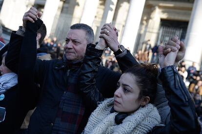 Varias personas se sujetan las manos durante un emotivo homenaje a las víctimas en Bruselas (Bélgica).