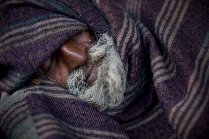 Un hombre sin hogar duerme cubierto con una manta en un barrio antiguo de Delhi, India. 