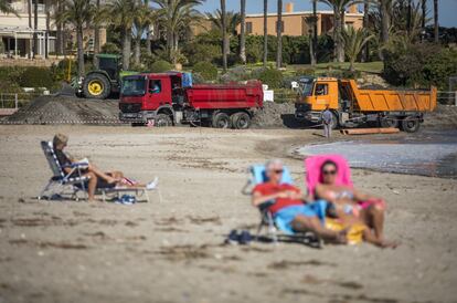 In Arenal Beach, beachgoers enjoy the warm weather, despite the presence of trucks transporting sand.