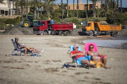 In Arenal Beach, beachgoers enjoy the warm weather, despite the presence of trucks transporting sand.