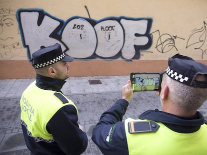 Agentes de la policía local de Málaga realizan fotos a uno de los grafitis aparecidos en una de las calles de la ciudad.