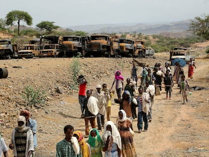 Aldeanos regresan de un mercado en Yechila, región de Tigray, junto a vehículos quemados durante el conflicto el pasado 10 de julio.