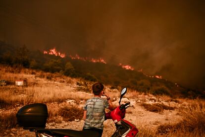 Un niño observa uno de los incendios forestales, en las afueras de Atenas, el martes 22 de agosto.