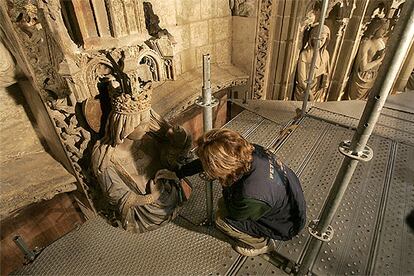 Una especialista trabaja en la restauración de una de las figuras del pórtico.