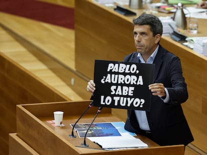 El president de la Generalitat, Carlos Mazón, muestra un cartel que alude al alcalde de Elche, Pablo Ruz, y a, su socia de gobierno Aurora Rodil, de Vox, durante su intervención en la sesión de control de las Cortes.