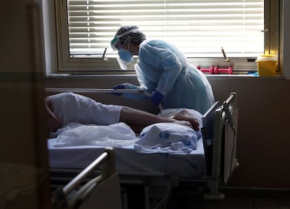Una sanitaria asiste a una persona con covid en el área de medicina interna del Hospital Gregorio Marañón de Madrid, en la primera ola de la pandemia.