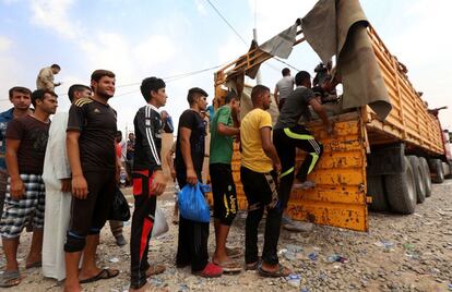 Refugiados iraquíes suben a un vehículo para trasladarse del campo de Dibaga hacia sus viviendas.