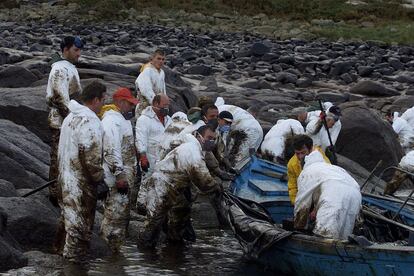 Percebeiros de Santa Mariña (A Coruña) trabajando en las labores de limpieza del vertido, en la zona de Pelouro (Costa da Morte). Arriba y en el centro de la foto, rubio con el pelo corto, Ivan Tajes Castro.