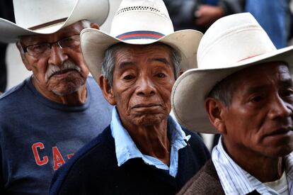 Tres hombres hacen cola para depositar su voto en un colegio electoral en San Juan Sacatepéquez.