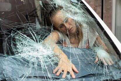 Una mujer protege el interior de un vehículo dañado por el granizo caído en La Bisbal de l'Empordà.