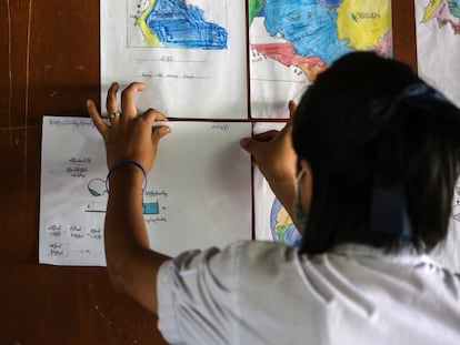 Aye Aye Than pega una tarea de ciencias en la pared de su clase en un Centro de Aprendizaje para Migrantes en Mae Sot, Tailandia, donde vive refugiada tras el golpe de estado militar en su país, Myanmar.