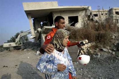 Un voluntario de la Cruz Roja intenta calmar a Jeinab Shalhoub, de 66 años, que ha perdido a varios miembros de su extensa familia en la matanza de Qana.