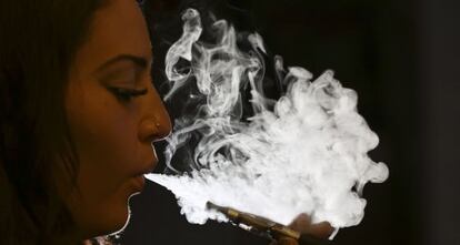Una dona exhala el vapor d'una cigarreta electrònica.