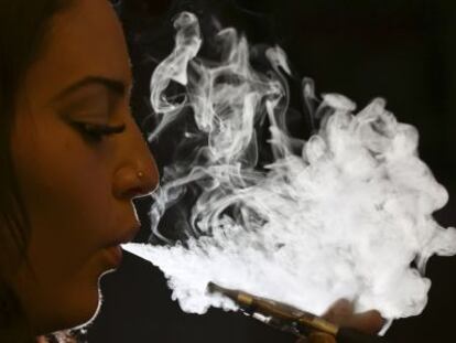 Una dona exhala el vapor d'una cigarreta electrònica.