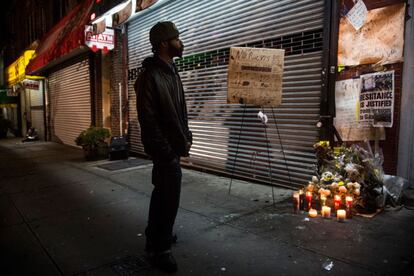 Un hombre se detiene en un altar improvisado para Eric Garner, en el mismo lugar donde fue estrangulado. El caso no se cierra con lo decidido en Staten Island. El fiscal general, Eric Holder, anunció que su departamento investigará lo sucedido con Garner como una posible violación de sus derechos civiles.