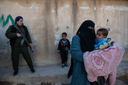 Una miliciana de las Fuerzas Internas de Seguridad del Norte y Este de Siria escolta a una mujer y sus hijos evacuadas del anexo para iraquíes del campo Al Hol. Más del 90% de los habitantes del campo son mujeres o niños, lo que ha favorecido una inusitada metamorfosis del movimiento terrorista en el que las féminas ocupan puestos de decisión y lideran acciones violentas, convirtiendo Al Hol en un minicalifato femenino. De ahí que sean las mujeres de los Assayish -Fuerzas Internas de Seguridad-, de las YAT y de las Unidades Femeninas de Protección popular (YPJ) las primeras en entrar en las tiendas para registrar a las mujeres yihadistas y agruparlas a la entrada del campo.