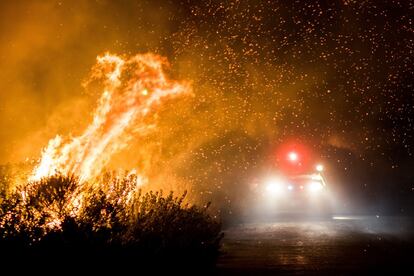 Los bomberos trabajan para extinguir el incendio de Thomas mientras quema se la carretera 101 hacia la autopista de la costa del Pacífico en Ventura, California.