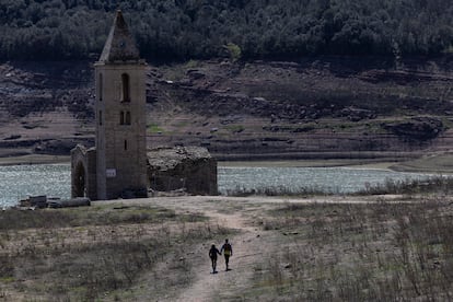 Dos personas pasean cerca del embalse de Sau, en la comarca de Osona, que se encuentra al 7,81% de su capacidad, este lunes en Girona.